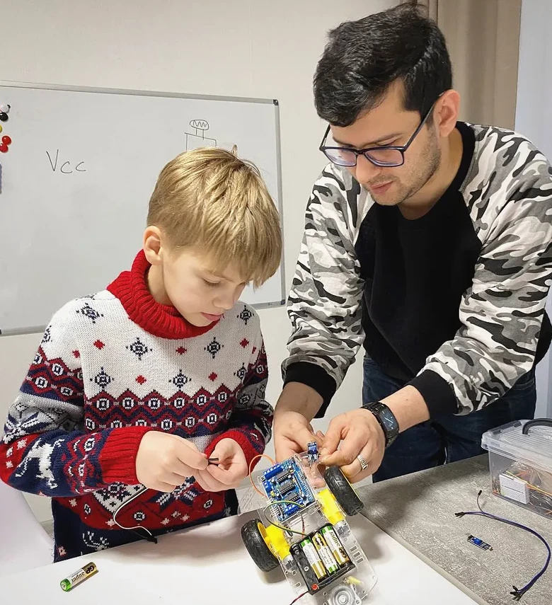 Ronnie guiding a young learner as they connect components on an Arduino robot