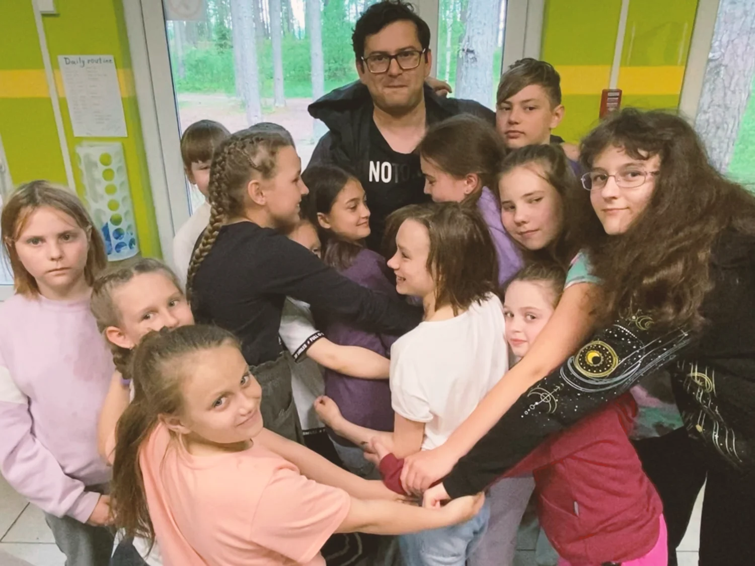 Ronnie surrounded by a group of young learners indoors
